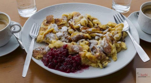 Bu görselde Avusturya’nın ünlü tatlısı Kaiserschmarrn sunulmaktadır. Hafif karamelleşmiş ve parçalanmış bu kabarık hamur tatlısı, üzerine pudra şekeri serpilerek tamamlanmış. Yanında ise geleneksel olarak servis edilen zwetschkenröster (erik kompostosu) yer alıyor. Kaiserschmarrn, gerek görünüşü gerekse tadıyla gerçek bir konfor yemeği sunuyor ve hem Avusturya’da hem de Bavyera’da büyük bir sevgiyle tüketiliyor. Tatlı bir kahve molasının eşlikçisi olan bu lezzet, hem basit malzemeleri hem de imparatorlara layık dokusuyla mutlaka denenmeli!