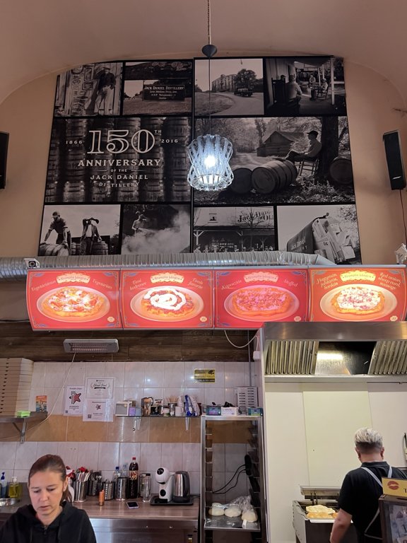 Krumplis Lángos’un yüksek tavanlı iç mekânı, menü panoları ve hazırlık tezgâhı