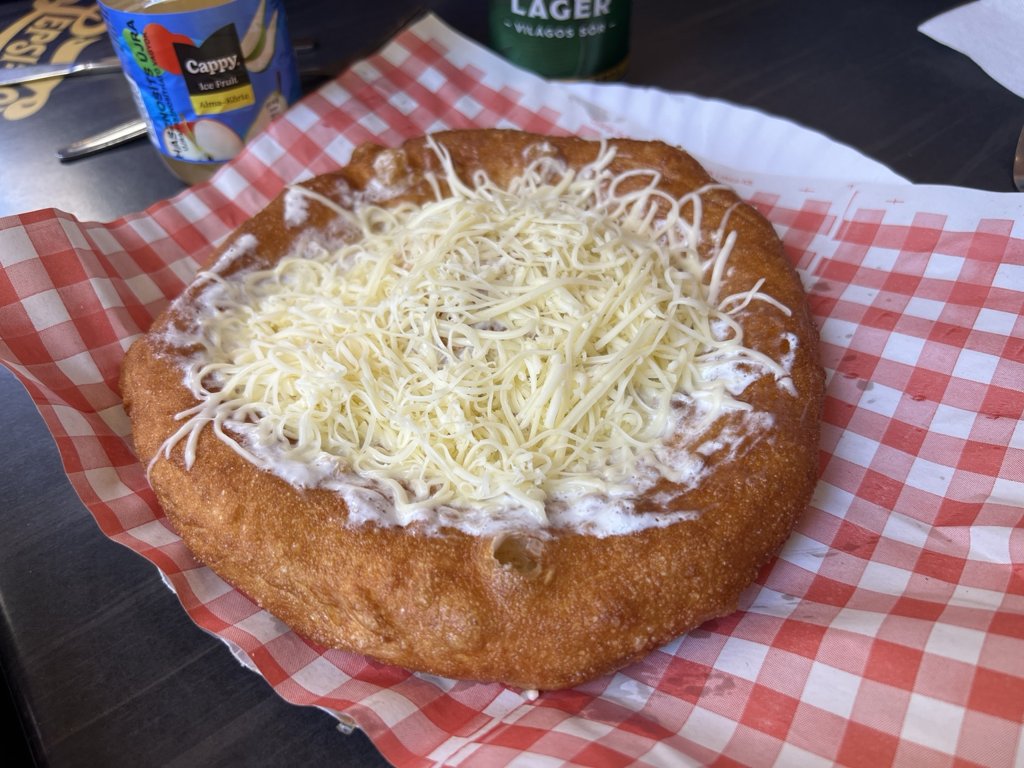 Kareli servis kâğıdı üzerinde ekşi krema ve rendelenmiş peynirli lángos
