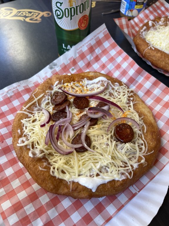 Masada servis edilen sucuk, kırmızı soğan ve peynirli lángos