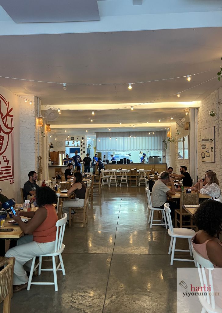 Muli São Paulo’nun açık mutfağı, ahşap masaları ve ışıklarla aydınlatılmış yemek salonu