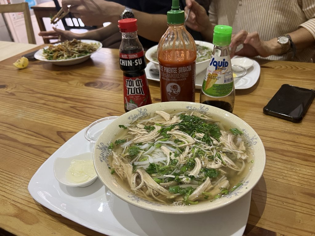 Pho Very Good’da pho kâseleri, noodle tabağı ve masadaki soslar
