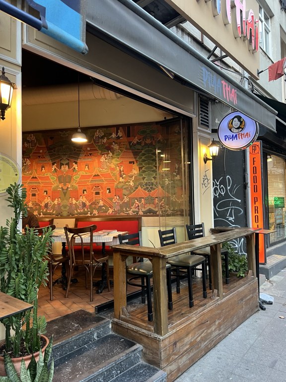 Piya Thai Kadıköy’ün girişi, önündeki masalar ve içerideki Tayland temalı duvar resmi