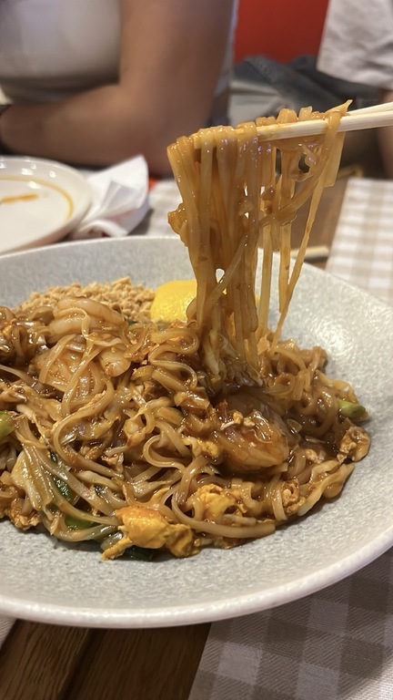 Çubuklarla kaldırılan pirinç noodle ve karidesli Pad Thai