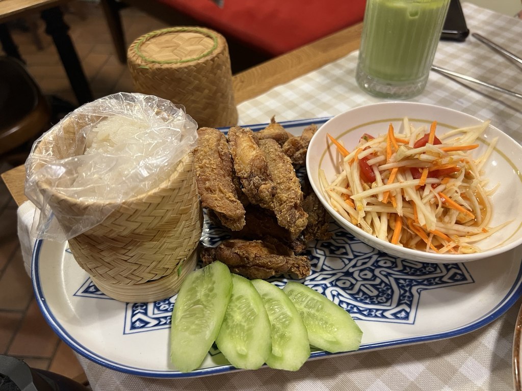 Papaya salatası, çıtır tavuk kanatları ve sepette yapışkan pirinç