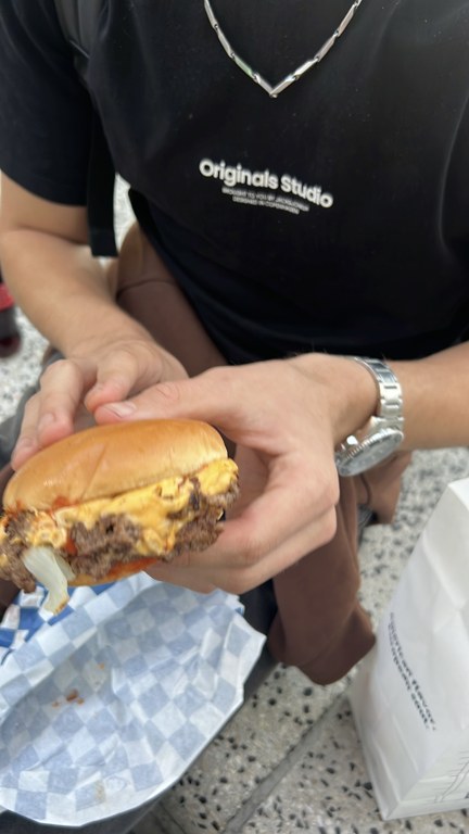 Elde tutulan Smashy cheeseburgerin köfteleri, erimiş peyniri ve soğanı
